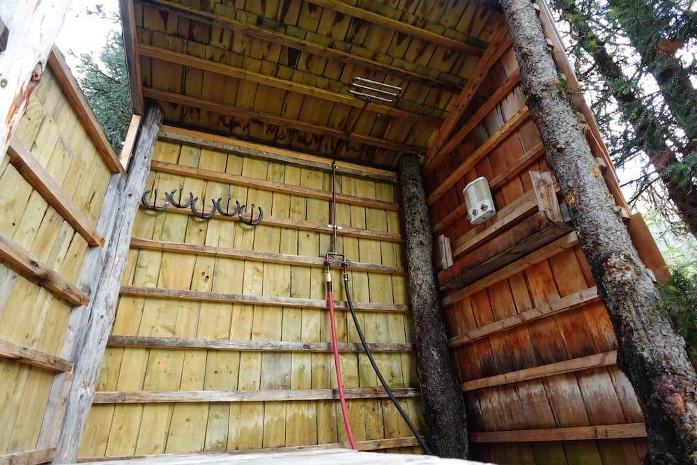 Outdoor shower at Halfway Lodge in Banff National Park, Alberta, Canada during the six-day horseback trip The outdoor shower at Halfway Lodge in Banff National Park, Alberta, Canada, built from simple wooden walls around trees with exposed hoses, hooks and a small water heater in the rustic backcountry setting.
