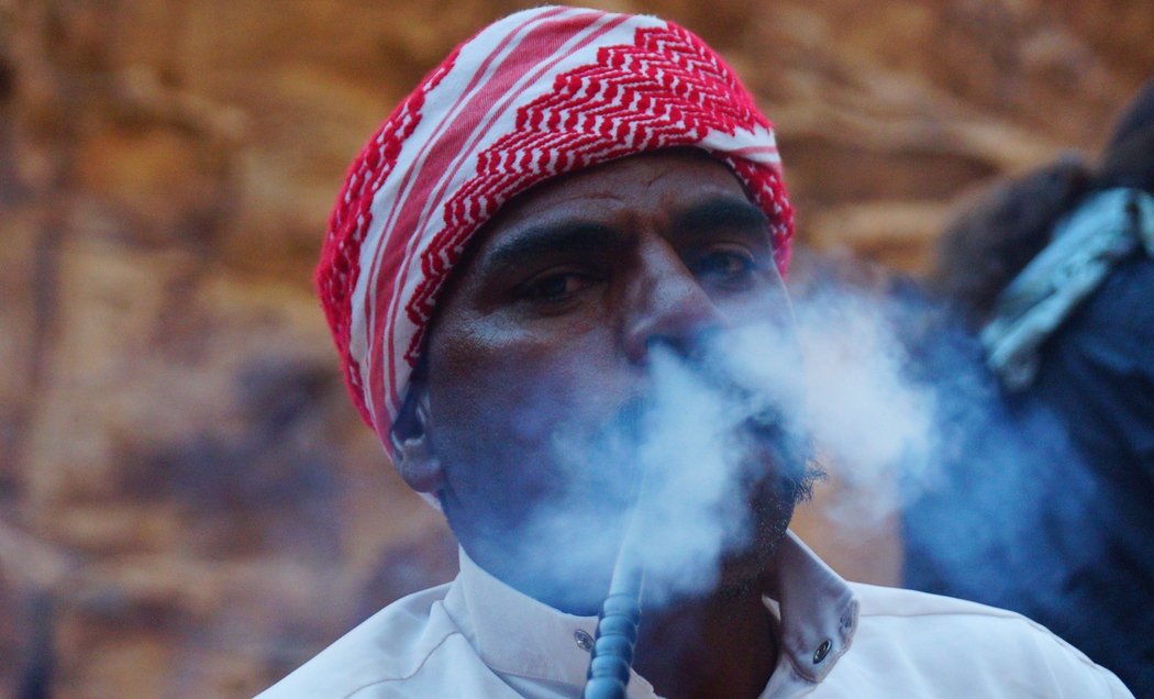 Here a Bedouin man puffs smoke out of his nose just outside of tent in Wadi Rum. Smoking hookah, know locally as Arghila or Shisha, is very common in Jordan.