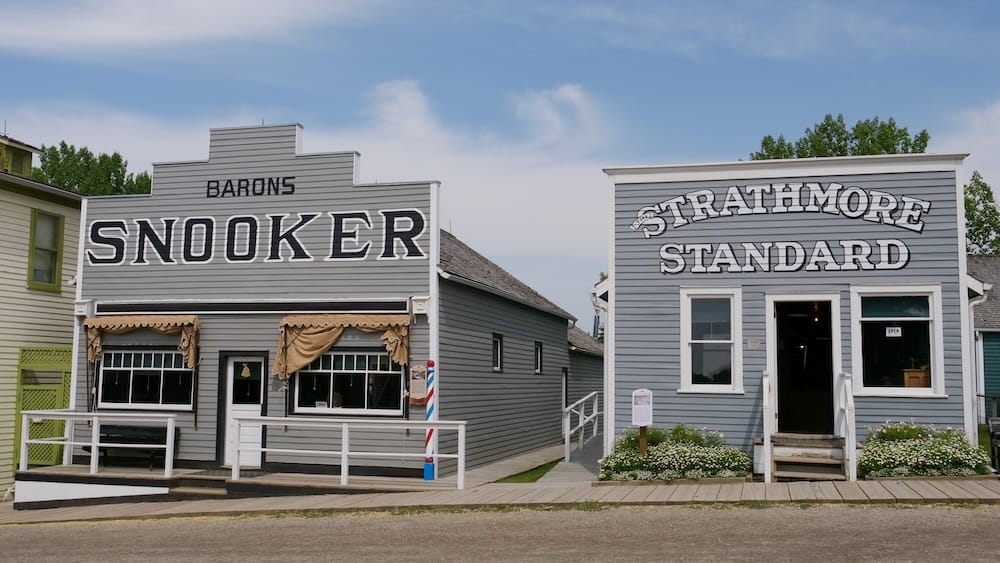 Historic Snooker hall and Strathmore Standard newspaper buildings along a recreated street at Heritage Park Historical Village in Calgary, Alberta, Canada.