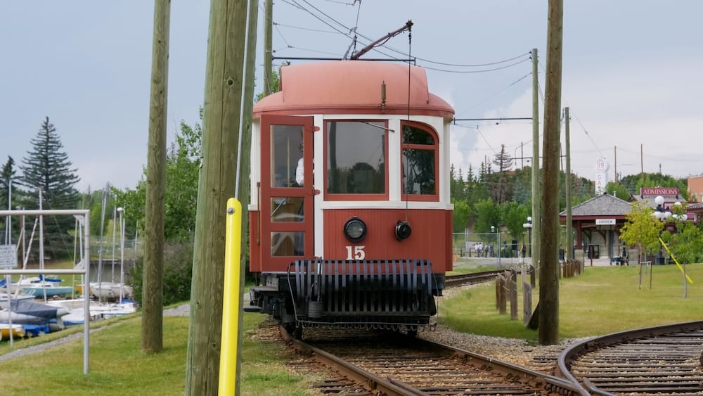 Heritage Park Electric Streetcar No. 15 Calgary Alberta Canada Historic Entrance Transportation Red electric streetcar No. 15 travels along the tracks near the entrance to Heritage Park in Calgary, Alberta, Canada, beneath overhead wires with the admissions area visible behind it.