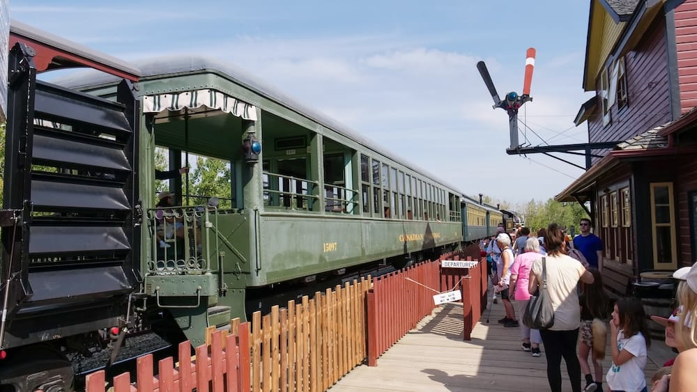 Steam train boarding platform at Heritage Park Historical Village, Calgary, Alberta, Canada Visitors queue along a wooden platform to board a vintage green "Canadian" railway passenger car numbered 1509T at Heritage Park Historical Village in Calgary, Alberta, Canada, with a semaphore signal overhead.