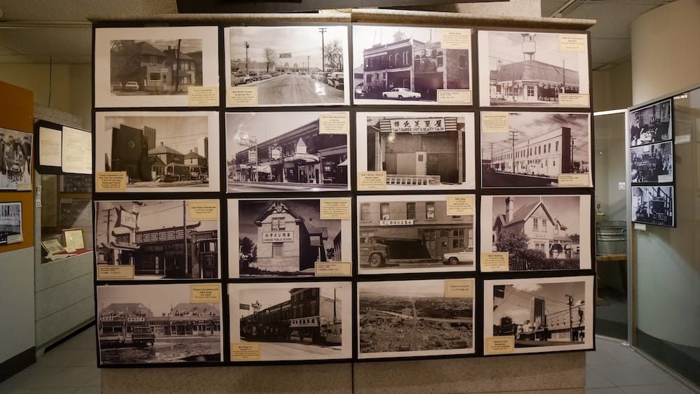 A wall of black-and-white archival photographs documenting early Chinatown buildings, businesses, and street scenes on display inside the Chinese Artifacts Museum in Calgary, Alberta, Canada.