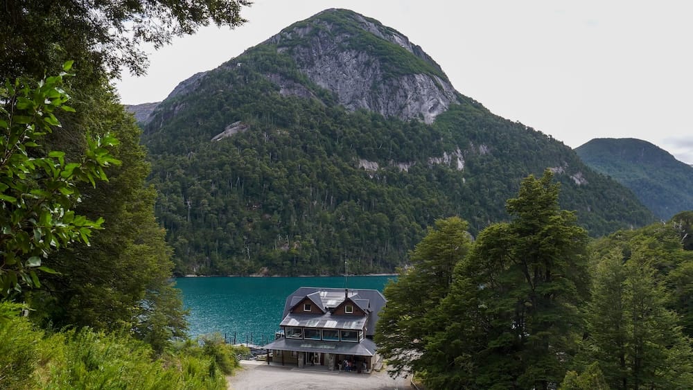 Hotel Puerto Blest beside turquoise Nahuel Huapi Lake, surrounded by dense forest and steep mountain slopes inside Nahuel Huapi National Park, Río Negro, Patagonia, Argentina.