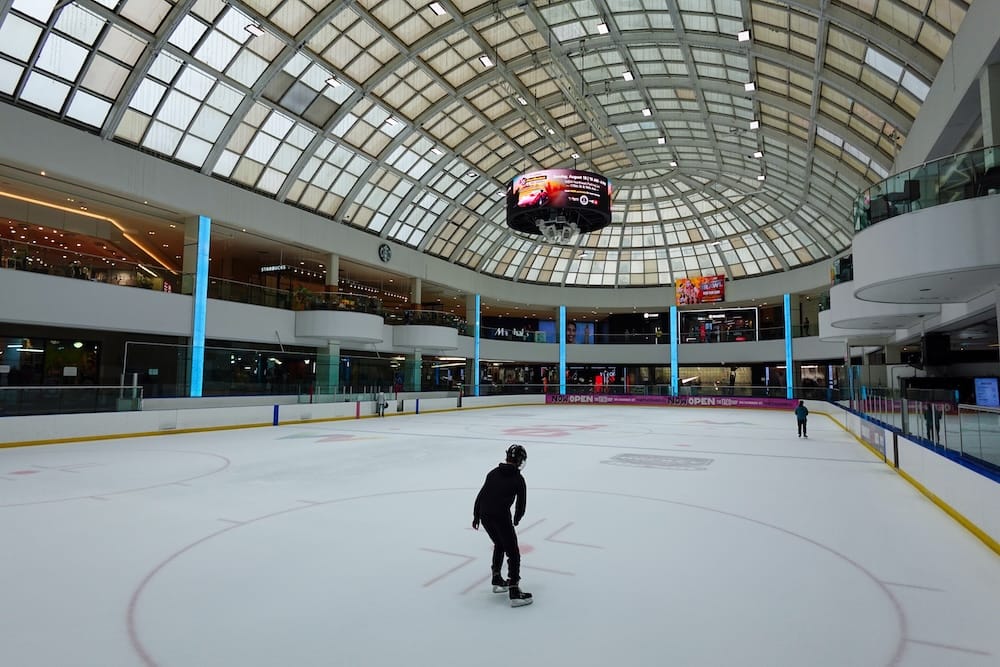 Ice Palace Skating Rink Inside West Edmonton Mall in Edmonton Skaters moving across the Ice Palace rink inside West Edmonton Mall in Edmonton, Alberta, beneath the curved glass roof and surrounded by shops, restaurants and upper-level walkways.