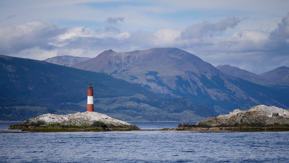 iconic red-and-white Les Eclaireurs Lighthouse labeled as the “End of the World” beacon from a distant vantage point on our boat tour in Ushuaia, Argentina