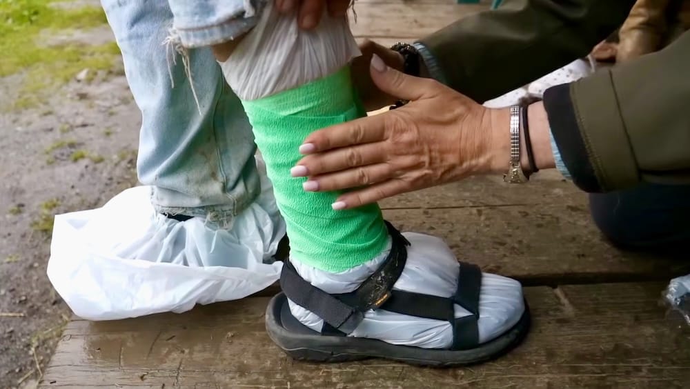 Calzado improvisado para la lluvia, Halfway Lodge, Parque Nacional Banff, Alberta, Canadá Una bolsa de plástico y un envoltorio verde se sujetan sobre una sandalia para improvisar protección contra la lluvia antes de una caminata húmeda en el Parque Nacional Banff, Alberta, Canadá.