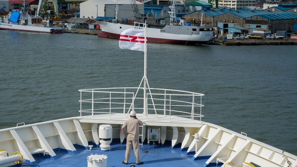 Japanese ferry worker on the deck with flag flapping in the wind