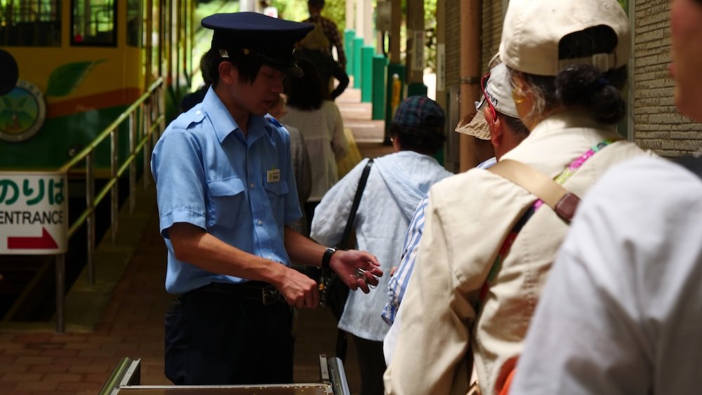 Japanese train conductor checking train tickets to Mount Takao, Japan 