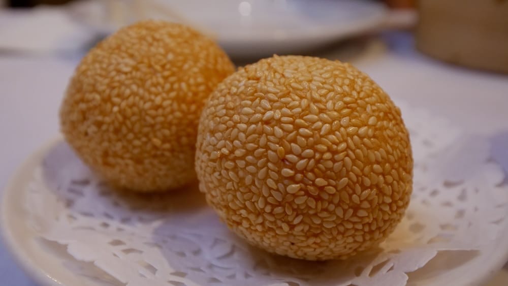 Sesame Balls (Jian Dui) at Silver Dragon Restaurant, Chinatown, Calgary, Alberta, Canada Two golden sesame balls, known as jian dui, plated on a doily at Silver Dragon Restaurant in Chinatown, Calgary, Alberta, Canada.
