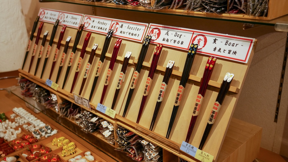 Japanese Zodiac Animal Chopsticks and Traditional Souvenir Display at Kanemori Red Brick Warehouses, Hakodate, Japan Display of decorative Japanese chopsticks inside a souvenir shop at the Kanemori Red Brick Warehouses in Hakodate, Hokkaido, Japan, arranged on wooden racks beneath zodiac animal labels including monkey, rooster, dog and boar.