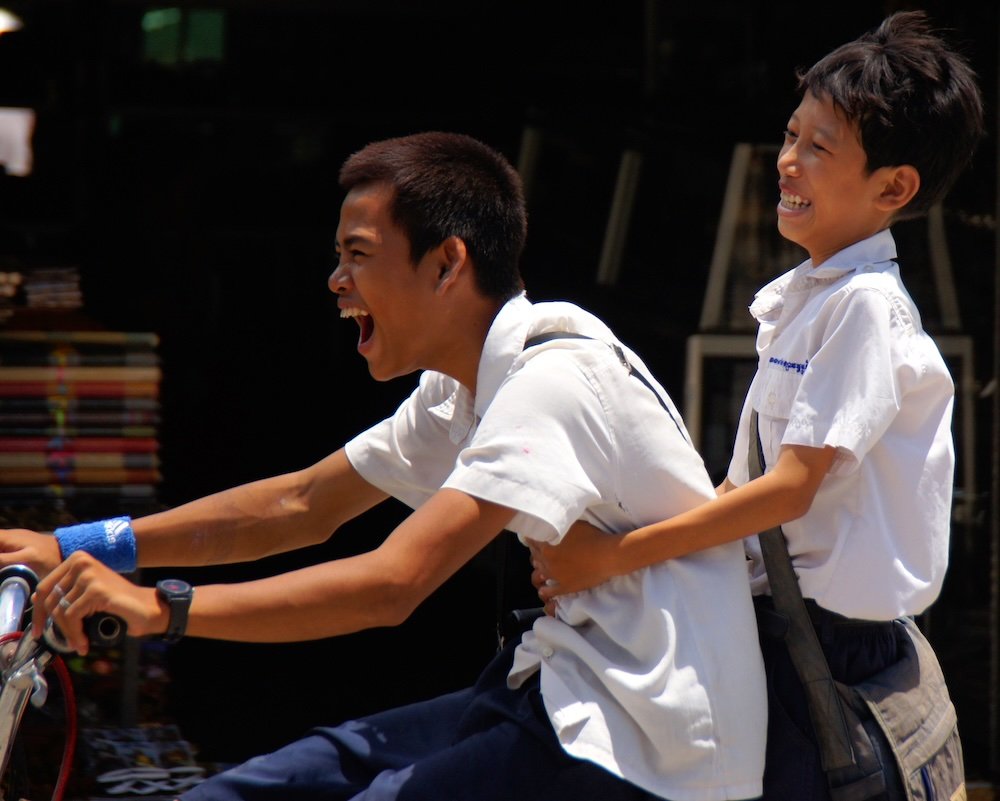 Khmer kids enthusiastically riding a bicycle in Siem Reap, Cambodia 