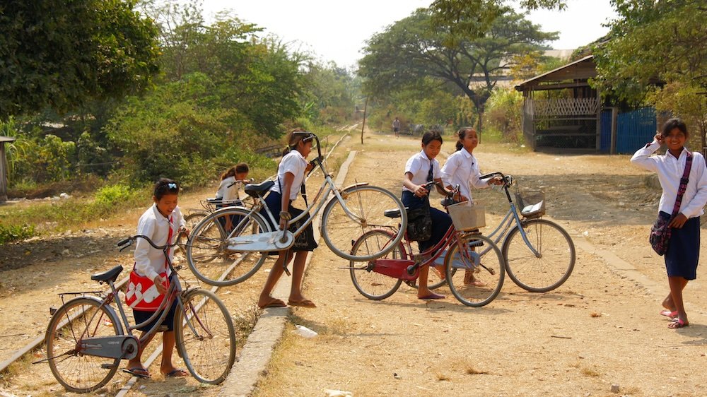 Khmer students crossing train tracks by bicycle in Battambang, Cambodia 