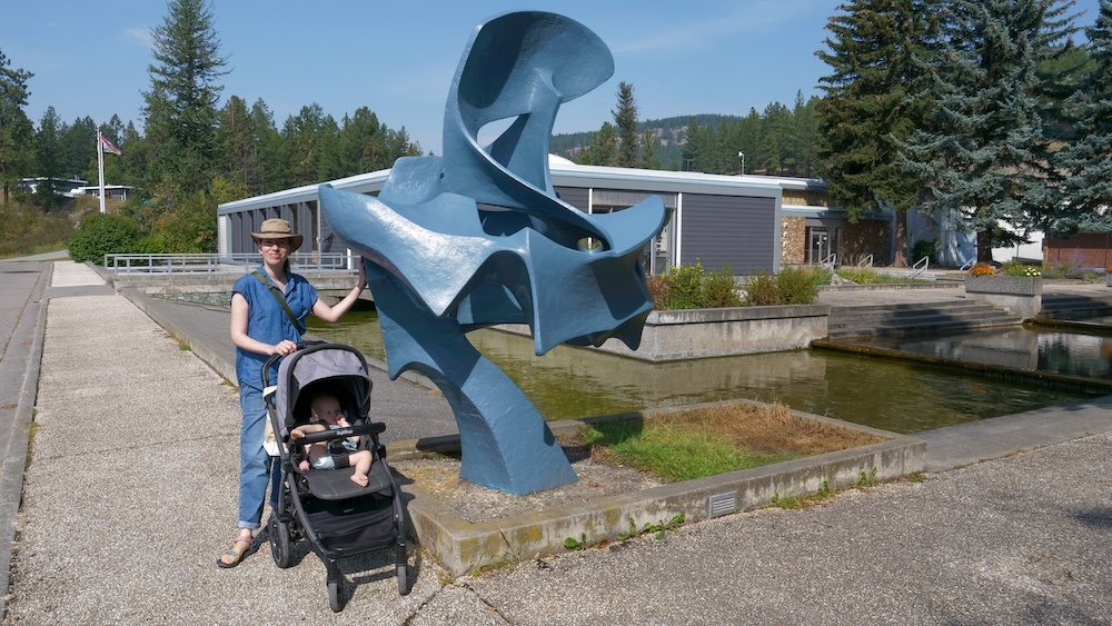 Kootenay Trout Hatchery near Cranbrook, BC, with outdoor ponds and sculpture as Audrey Bergner and baby Aurelia enjoy an easy, stroller-friendly family visit—an ideal day trip stop for families exploring the East Kootenays.