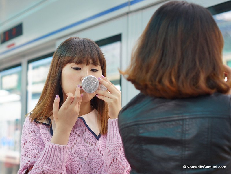 Korean lady putting on make-up waiting to catch the subway - South Korea