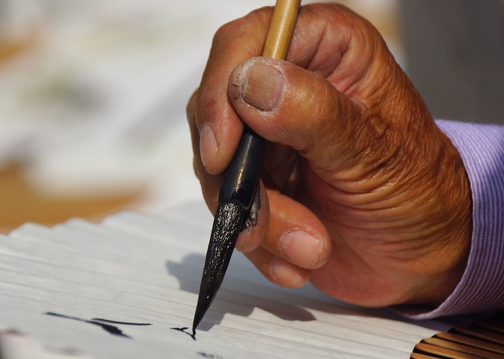 Korean man macro shot creating calligraphy on a personal fan in Insadong, Seoul, Korea 