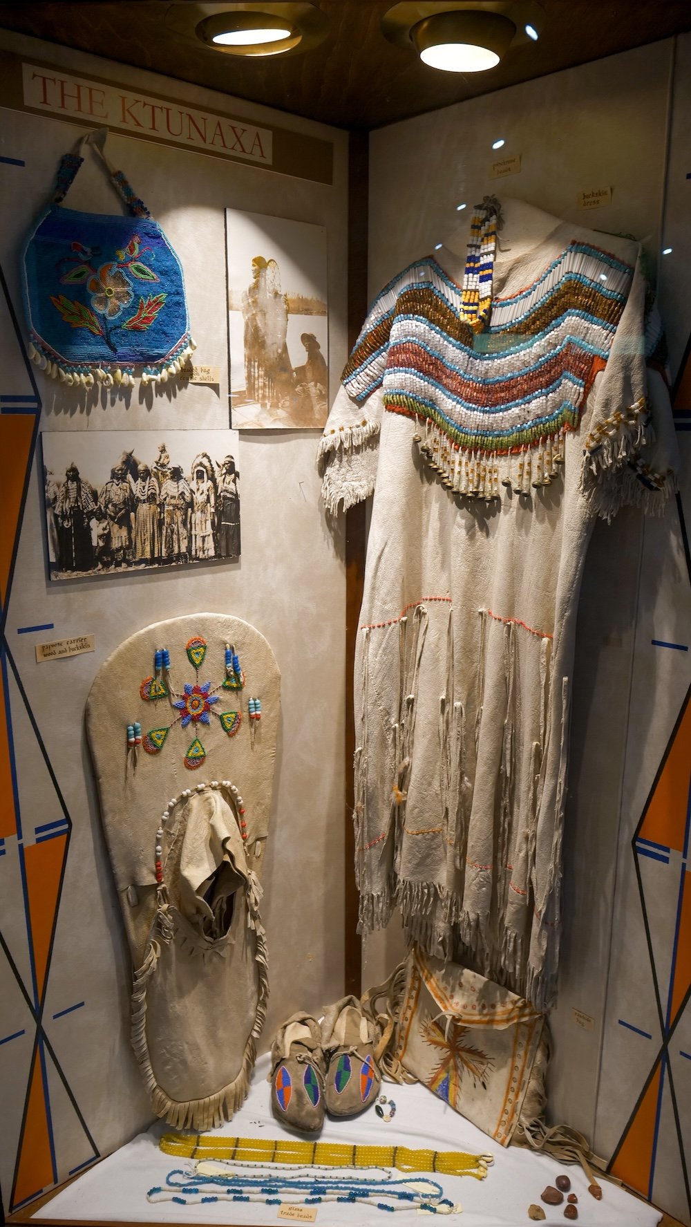 Fort Steele Heritage Town near Cranbrook, British Columbia, featuring a Ktunaxa cultural display with traditional garments, beadwork, moccasins, and historic photographs, offering insight into Indigenous craftsmanship and cultural history within the museum setting.