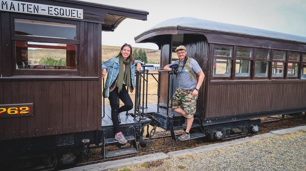 La Trochita Esquel Patagonia historic train with Samuel Jeffery and Audrey Bergner railway experience Esquel, Patagonia Argentina — Samuel Jeffery and Audrey Bergner standing between historic La Trochita train carriages, capturing the charm of this iconic narrow-gauge railway and one of the most memorable heritage travel experiences in Patagonia.