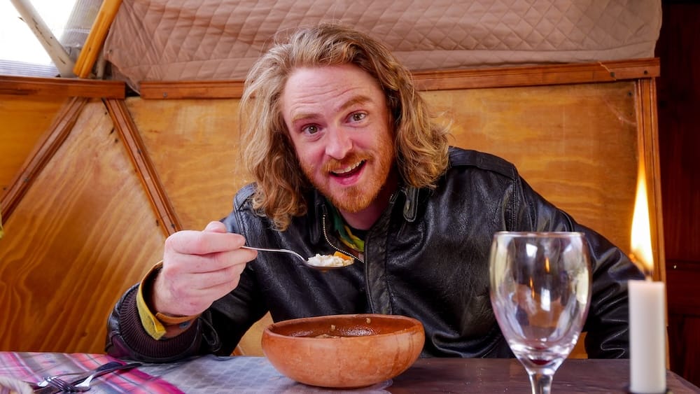 Samuel Jeffery enjoying a warm meal inside a rustic wooden cabin near Lago Gutiérrez in Bariloche Patagonia Argentina, highlighting cozy indoor dining experiences in the Patagonian Andes.

