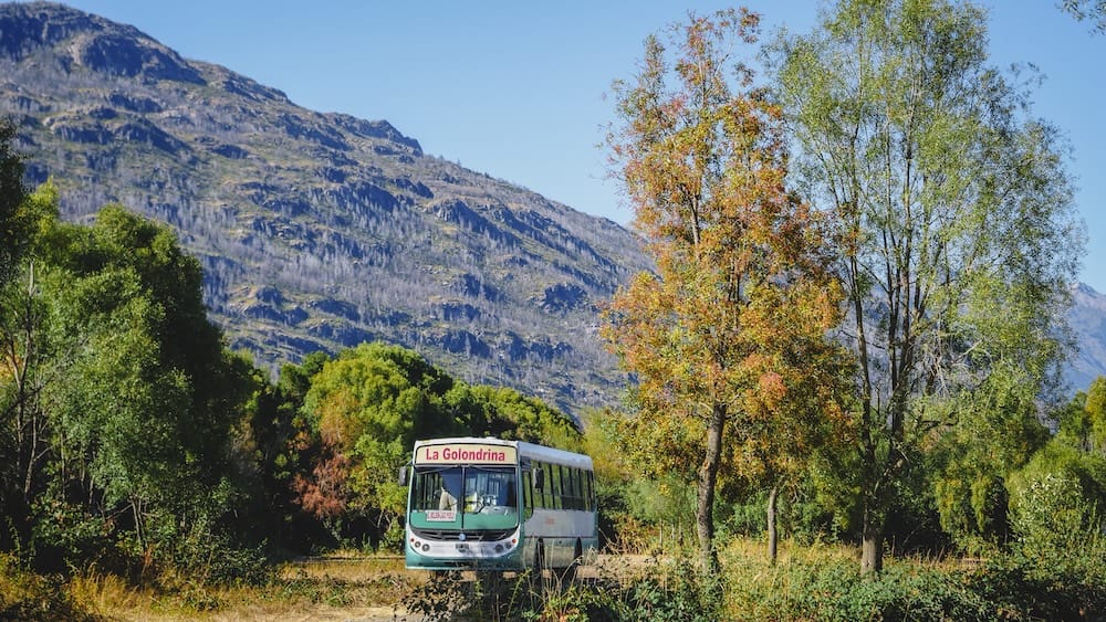 Lago Puelo Patagonia Argentina local bus La Golondrina traveling through rural landscape with mountains and trees showing small town transport reality and limited public transit options across provincial Patagonia routes