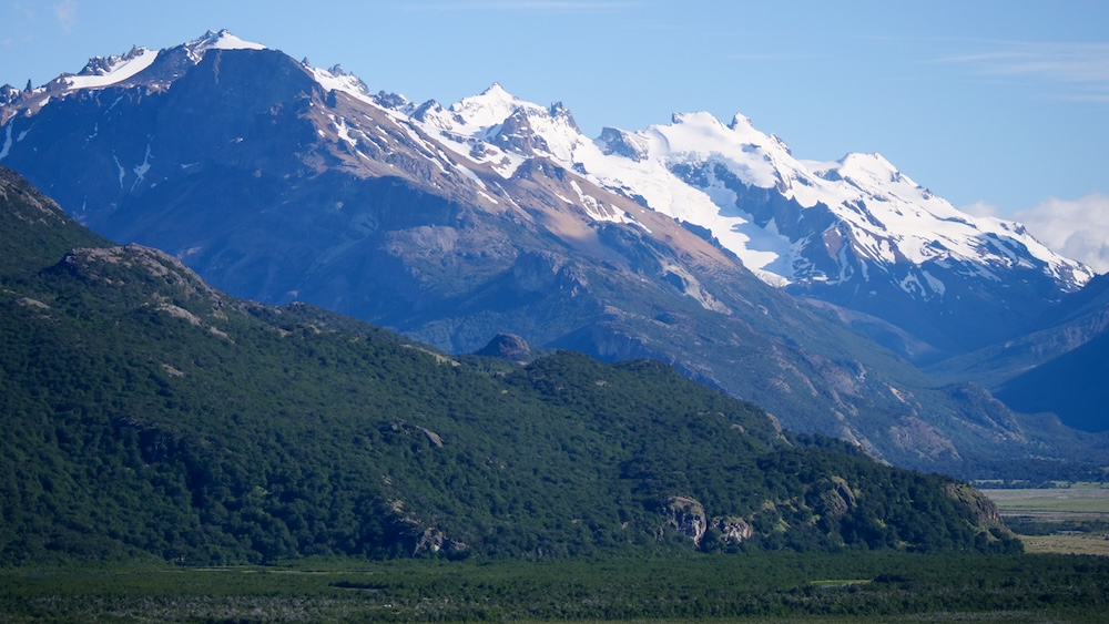 Laguna de los Tres hike in El Chaltén, Patagonia, showcasing sweeping mountain vistas, snow-capped peaks, and lush valleys under clear skies, giving hikers a glimpse of the dramatic Fitz Roy landscape along the iconic trail.