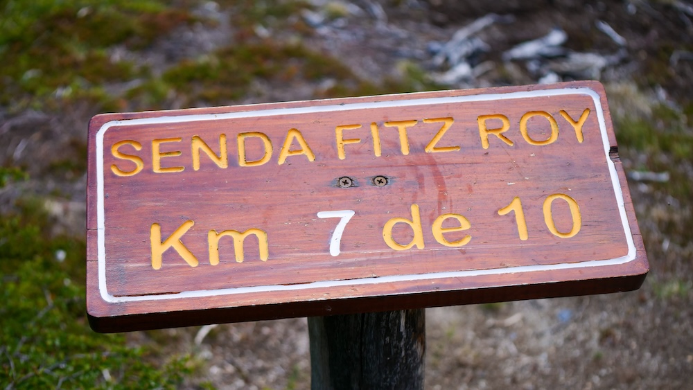Laguna de los Tres trail in El Chaltén, Patagonia, featuring a wooden kilometre marker sign reading “Senda Fitz Roy Km 7 de 10,” highlighting the unique progress-tracking system that helps hikers pace themselves on the iconic trek.