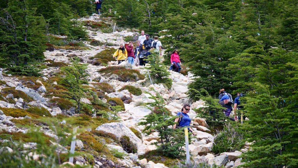 Hikers navigating the steep rocky KM 9 section of the Laguna de los Tres trail in El Chalten Patagonia where the crowded bottleneck highlights both the difficulty of the climb and the scale of the terrain leading toward Fitz Roy
