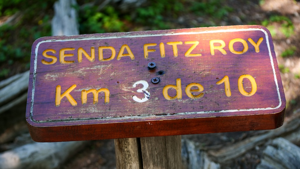 Laguna de los Tres trail marker sign in El Chaltén, Patagonia, showing “Senda Fitz Roy Km 3 de 10,” a wooden distance post on the iconic hike toward Mount Fitz Roy, guiding trekkers deeper into Argentina’s hiking capital.