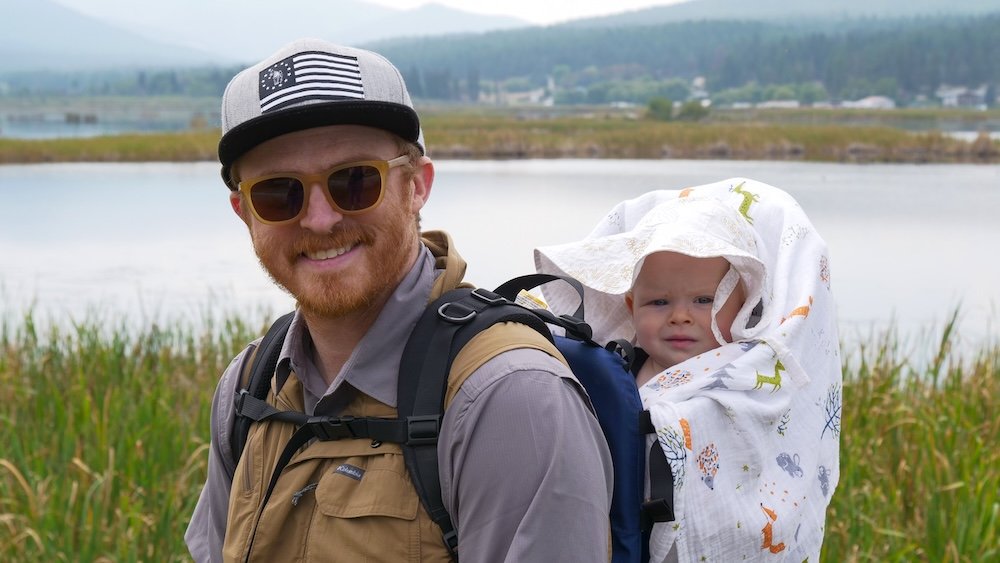 Family-friendly hiking at Lake Elizabeth in Cranbrook, BC with Nomadic Samuel and baby Aurelia Lake Elizabeth in Cranbrook, BC during a family-friendly hike, with Nomadic Samuel carrying baby Aurelia in a backpack carrier while exploring the calm wetland trails, showing how easy and accessible outdoor adventures are for parents traveling with babies.