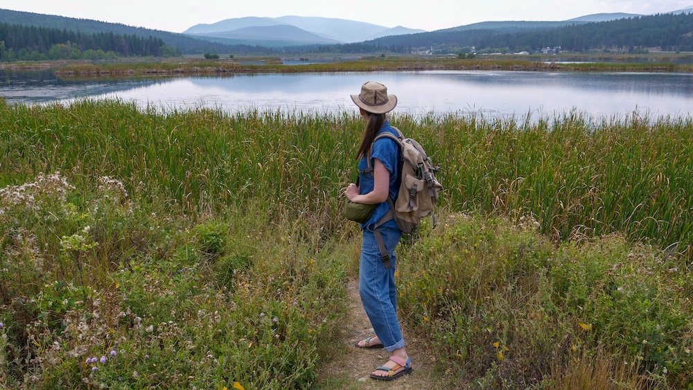 Scenic nature walk at Lake Elizabeth in Cranbrook, BC with Audrey Bergner Lake Elizabeth in Cranbrook, BC on a quiet nature walk, with Audrey Bergner pausing along the wetland trail to admire the calm water and mountain views, capturing why this peaceful, stroller-friendly area is ideal for slow family travel with babies and toddlers.