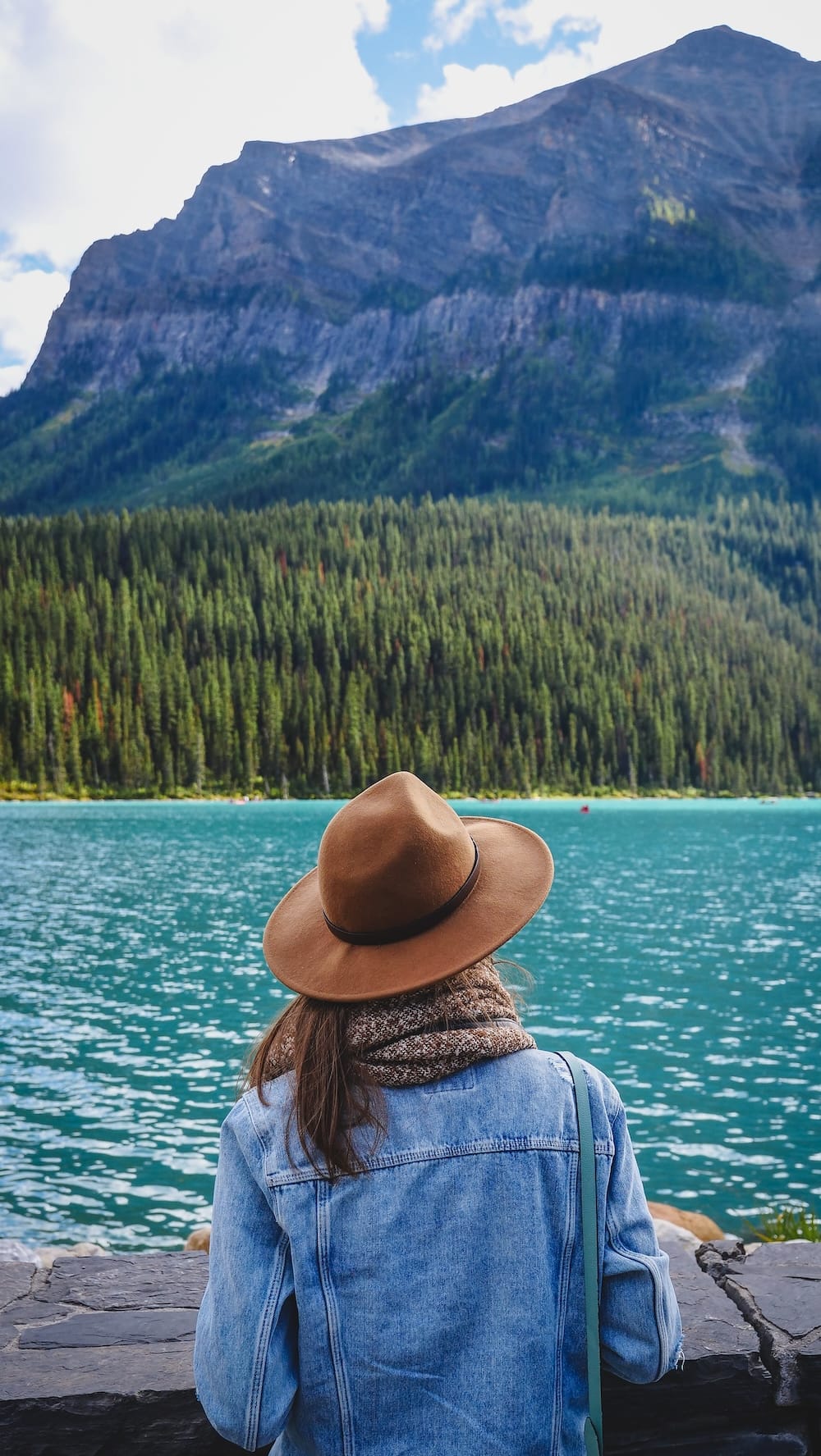 Audrey Bergner at Lake Louise in Banff National Park, Alberta, Canada, with turquoise water and mountain scenery Audrey Bergner looks across the turquoise water of Lake Louise in Banff National Park, Alberta, Canada, with dense evergreen forest and a steep Rocky Mountain slope rising beyond the lakeshore.