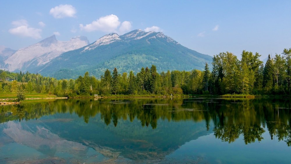 Lake Maiden reflections in Fernie Lake Maiden in Fernie, British Columbia, reflecting forested hills and Rocky Mountain peaks on a calm summer day, with glassy water, lakeside paths, and alpine scenery that make this easy walk a favorite stop for families visitors.