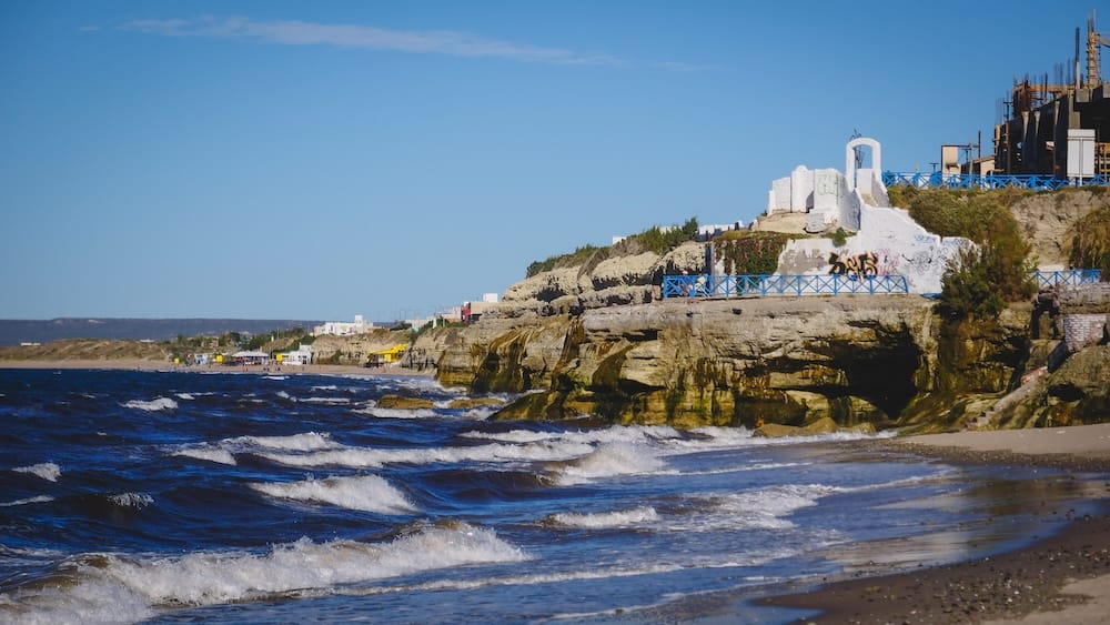 Las Grutas Patagonia coastal cliffs and Atlantic waves scenic beach views in Río Negro Argentina Las Grutas, Río Negro Patagonia — rugged coastal cliffs and Atlantic waves rolling onto sandy beaches, with seaside viewpoints and town structures above, showcasing the unique tidal landscapes of this underrated Patagonian beach destination.