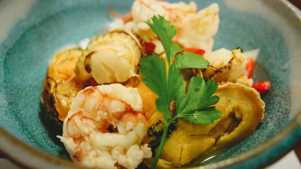 Fresh Patagonian seafood platter with shrimp, scallops, and shellfish served in a rustic ceramic bowl in Las Grutas, Río Negro, Argentina, showcasing the briny, warm-water Gulf of San Matías mariscos typical of coastal Patagonia cuisine.