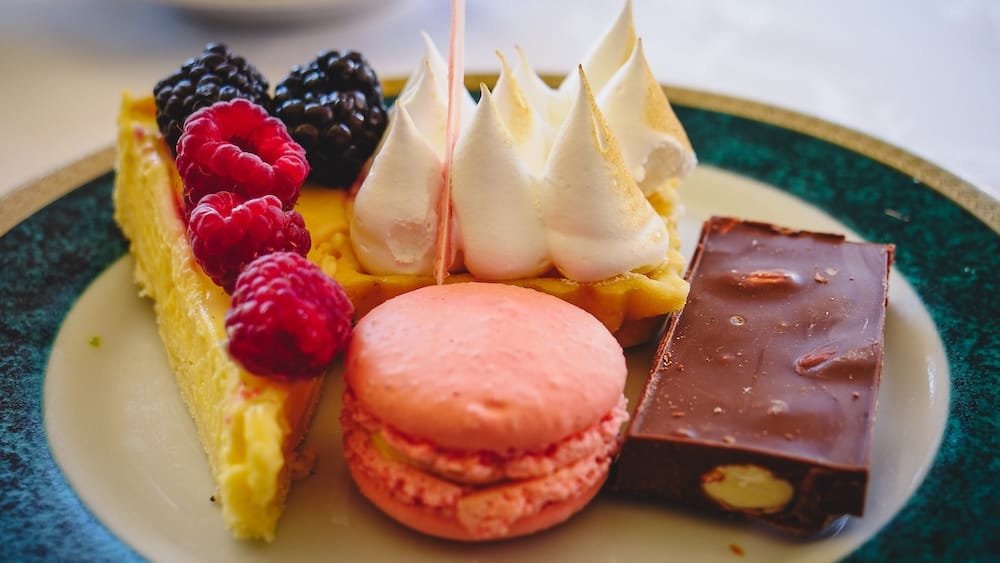 Lemon Meringue Tart, Berry Cheesecake, Macaron and Chocolate at Llao Llao Hotel Afternoon Tea A dessert plate at Llao Llao Hotel's afternoon tea holds a lemon tart with torched meringue peaks, a slice of berry cheesecake topped with raspberries and blackberries, a pink macaron, and a chocolate square with almonds in Bariloche, Río Negro, Argentine Patagonia.