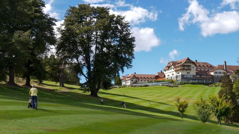 Llao Llao golf course fairway with hotel view, Bariloche, Río Negro, Argentine Patagonia Golfers walking a manicured fairway on Llao Llao's golf course, with the hotel's stone-and-wood alpine facade visible on the hill beyond, near Bariloche, Río Negro, in Argentine Patagonia.