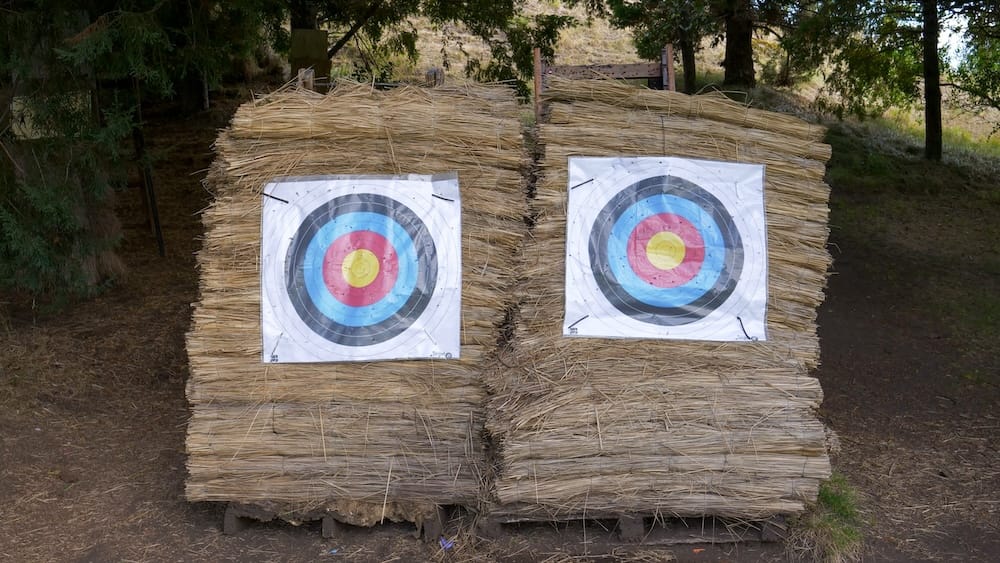 Two circular archery targets are mounted on stacked straw bales in a wooded outdoor activity area at Llao Llao Hotel in Bariloche, Río Negro, Patagonia, Argentina.