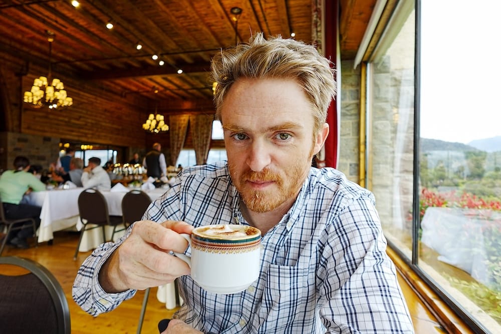 Samuel Jeffery Drinking Cappuccino at Breakfast in Llao Llao Hotel, Bariloche, Río Negro, Patagonia, Argentina Samuel Jeffery holds a cappuccino during breakfast at Llao Llao Hotel in Bariloche, Río Negro, Patagonia, Argentina, with the wood-lined dining room, buffet service and mountain views visible behind him.