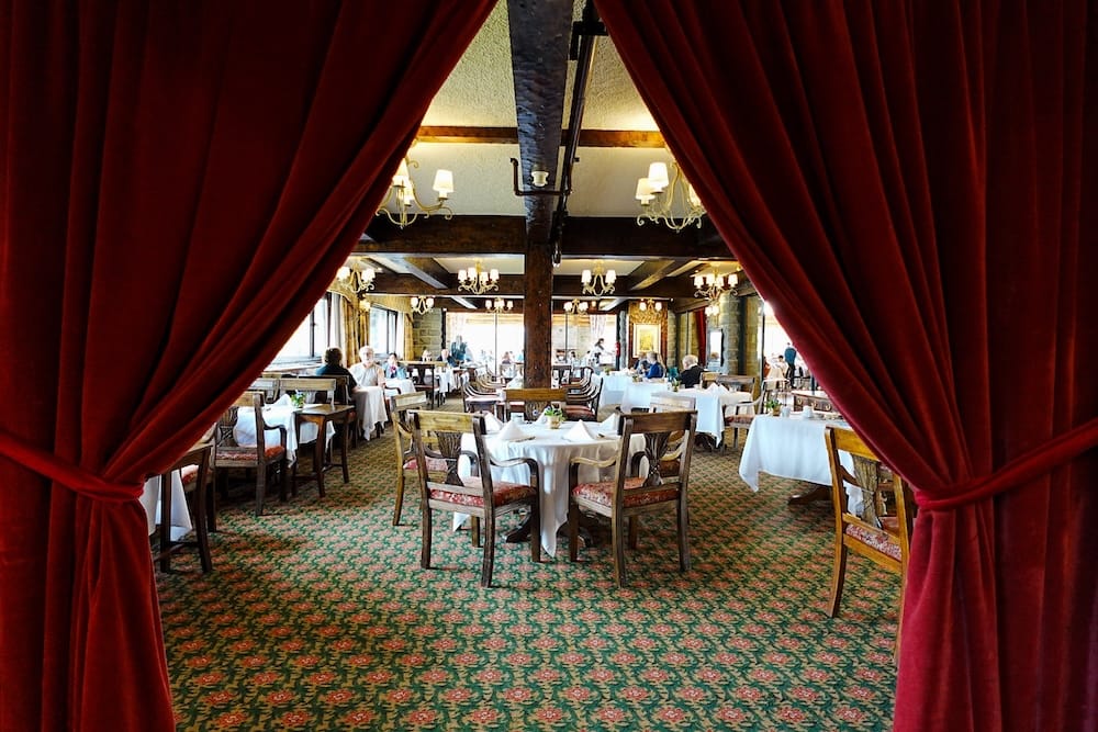 Elegant Dining Room with Red Velvet Curtains at Llao Llao Hotel, Bariloche, Río Negro, Patagonia, Argentina Elegant dining room at Llao Llao Hotel in Bariloche, Río Negro, Patagonia, Argentina, framed by deep red velvet curtains with white-clothed tables, timber beams, chandeliers and classic lodge interiors beyond.