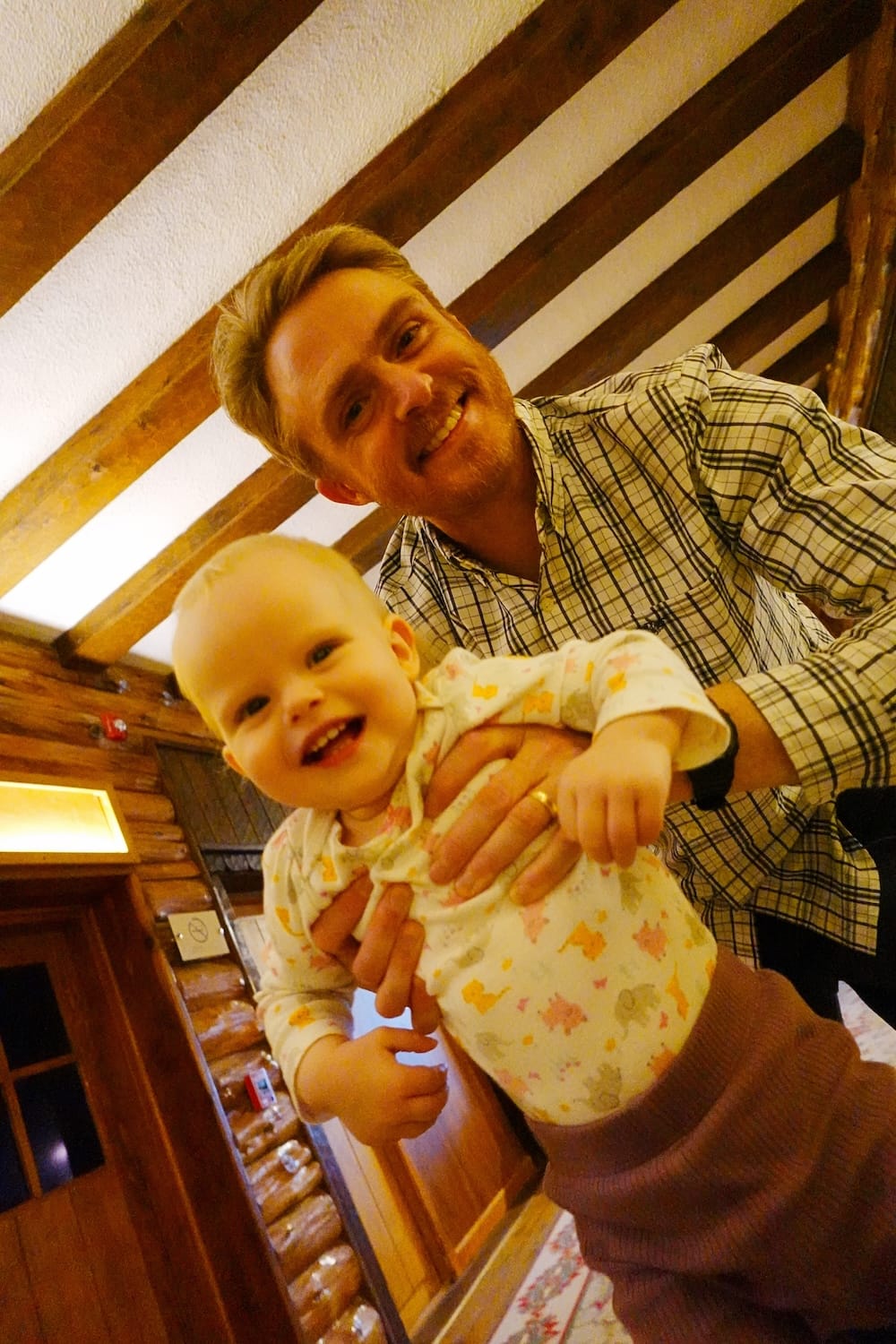 Bustillo Wing Room with Samuel Jeffery and Aurelia Jeffery, Llao Llao Hotel, Bariloche, Patagonia Samuel Jeffery smiles while holding daughter Aurelia beneath the exposed log-beam ceiling of a Bustillo Wing room at Llao Llao Hotel, Bariloche, Río Negro, Argentine Patagonia.