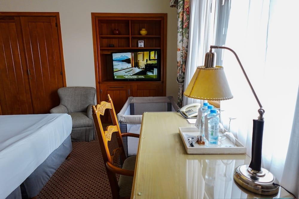 Bustillo Wing Room Interior with Desk and Crib, Llao Llao Hotel, Bariloche, Río Negro, Patagonia A Bustillo Wing guest room at Llao Llao Hotel with a wooden desk, welcome tray, armchair, closet, and a crib set up beside the bed, Bariloche, Río Negro, Argentine Patagonia.