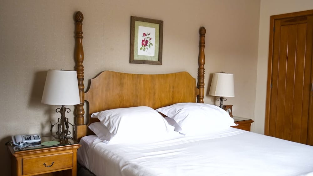 Two-Post Wooden Bed, Bustillo Wing Room, Llao Llao Hotel, Bariloche, Río Negro, Patagonia A two-post carved wooden bed with white linens and matching bedside lamps in a Bustillo Wing guest room at Llao Llao Hotel, Bariloche, Río Negro, Argentine Patagonia.