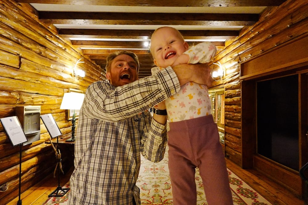Samuel Jeffery lifts a laughing Aurelia Jeffery inside a rustic log-lined hallway at Llao Llao Hotel in Bariloche, Río Negro, Patagonia, Argentina, where she loved running and playing during the family stay.