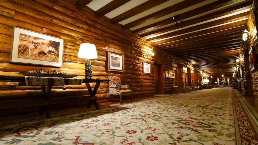 A long corridor of exposed cypress log walls at the Llao Llao Hotel, lined with framed wildlife photography and a patterned rug runner, San Carlos de Bariloche, Rio Negro, Argentine Patagonia.