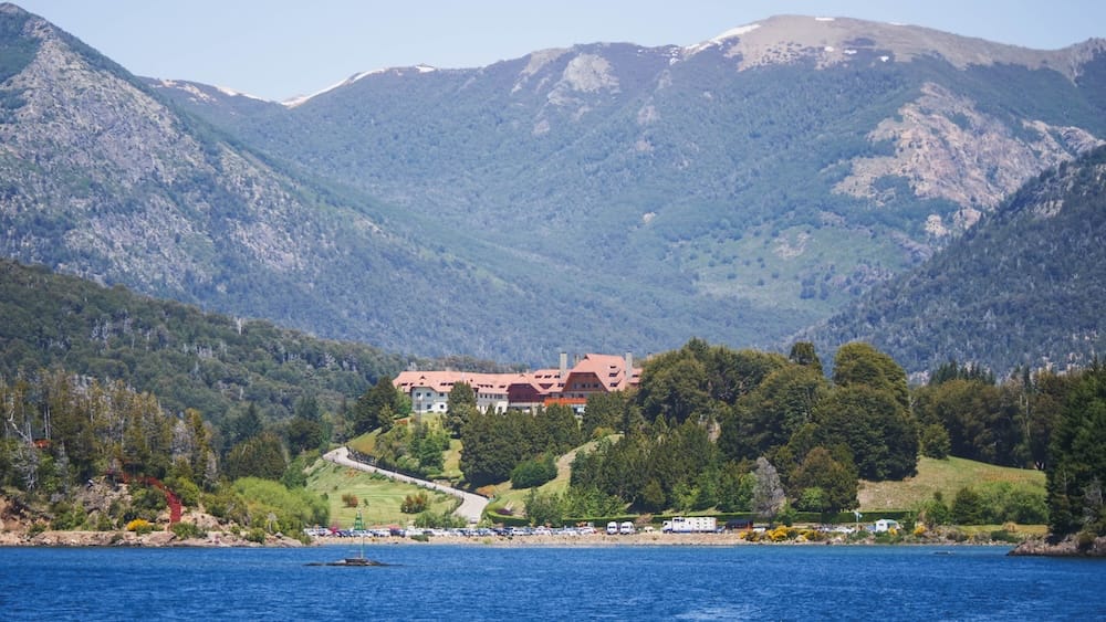 Llao Llao Hotel above Nahuel Huapi Lake in Bariloche, Patagonia, Argentina Llao Llao Hotel stands above the forested shoreline of Nahuel Huapi Lake in Bariloche, Río Negro, Patagonia, Argentina, with blue water in the foreground and rugged mountain slopes rising behind the property.