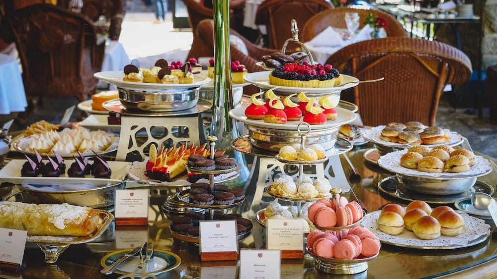 Afternoon Tea Dessert and Sandwich Buffet Spread at Llao Llao Hotel, Bariloche, Río Negro, Argentine Patagonia A tiered silver buffet spread of pink macarons, berry tarts, chocolate pastries, mini sandwiches, and brioche buns laid out for afternoon tea at Llao Llao Hotel's terrace in Bariloche, Río Negro, Argentine Patagonia, Argentina.
