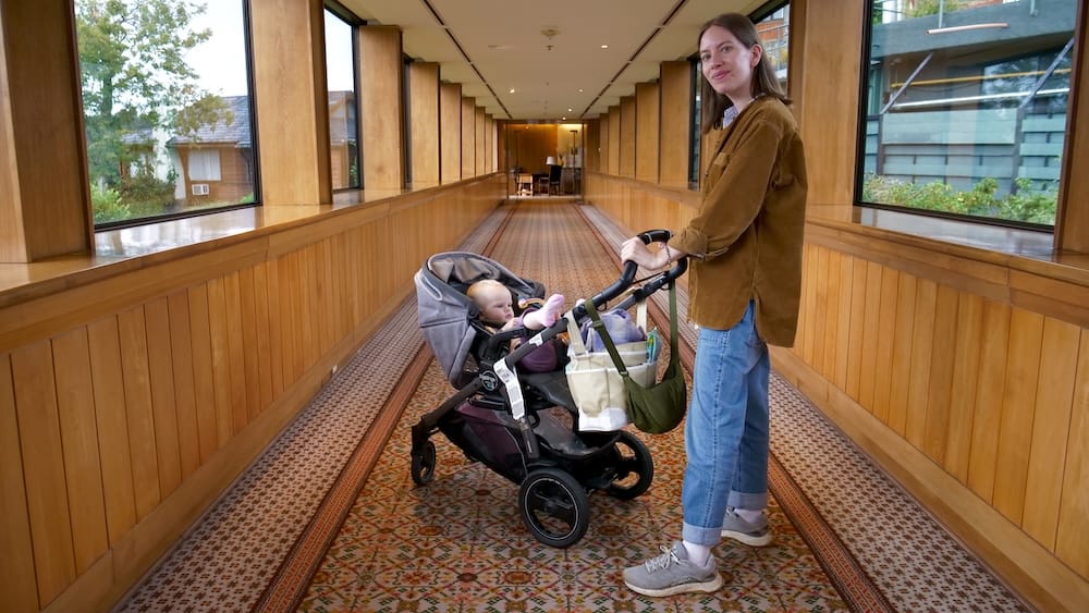 Wood-Paneled Corridor with Audrey Bergner and Aurelia Jeffery, Llao Llao Hotel, Bariloche, Patagonia Audrey Bergner pushes daughter Aurelia in a stroller through a long wood-paneled corridor with windows on both sides at Llao Llao Hotel in Bariloche, Río Negro, Argentine Patagonia.