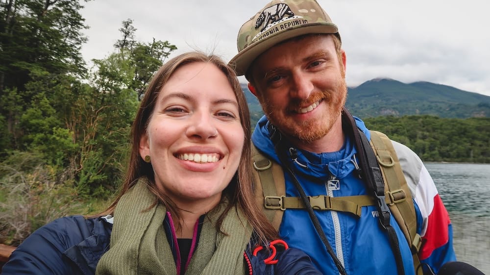 Samuel Jeffery and Audrey Bergner Beside a Glacial Lake in Los Alerces National Park, Patagonia Samuel Jeffery and Audrey Bergner smile beside a clear glacial lake framed by forest and cloud-covered mountains in Los Alerces National Park, Chubut, Patagonia, Argentina.