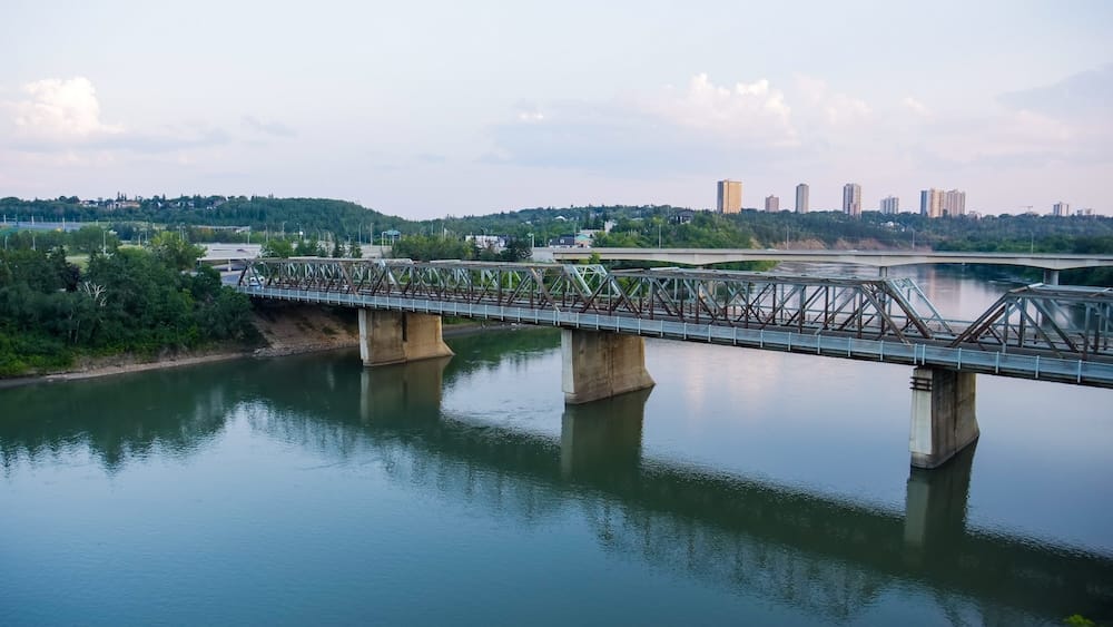The steel-truss Low Level Bridge spans the North Saskatchewan River with Edmonton's downtown skyline in the distance, a view visible from the Frederick G. Todd Lookout at the base of the 100 Street Funicular, Alberta, Canada.
