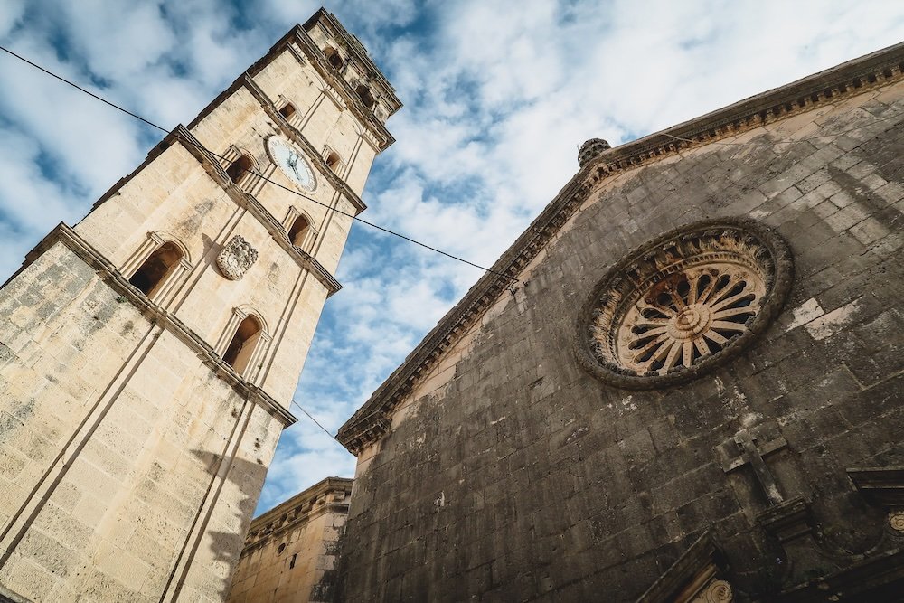 Low vantage point looking up at St. Nikola Church standing tall with its imposing bell tower in Perast, Montenegro