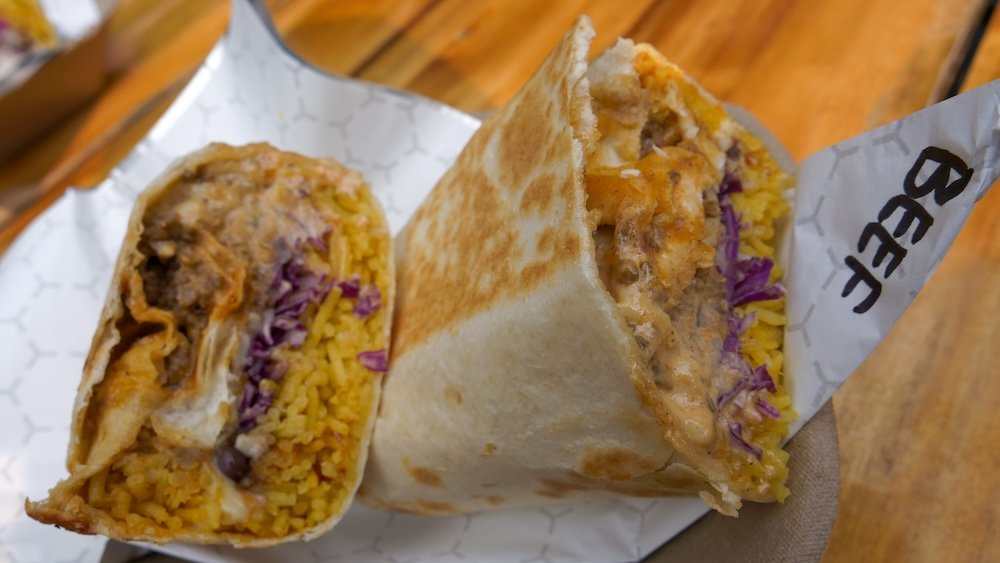 Beefy Boy Burrito Macro Detail at Luchadora Burrito Co. in Fernie, BC Fernie, British Columbia macro food shot of the Beefy Boy burrito from Luchadora Burrito Co., sliced open to show Tex-Mex ground beef, spicy yellow rice, black beans, shredded purple cabbage, melted cheese, and chipotle aioli wrapped in a toasted tortilla.